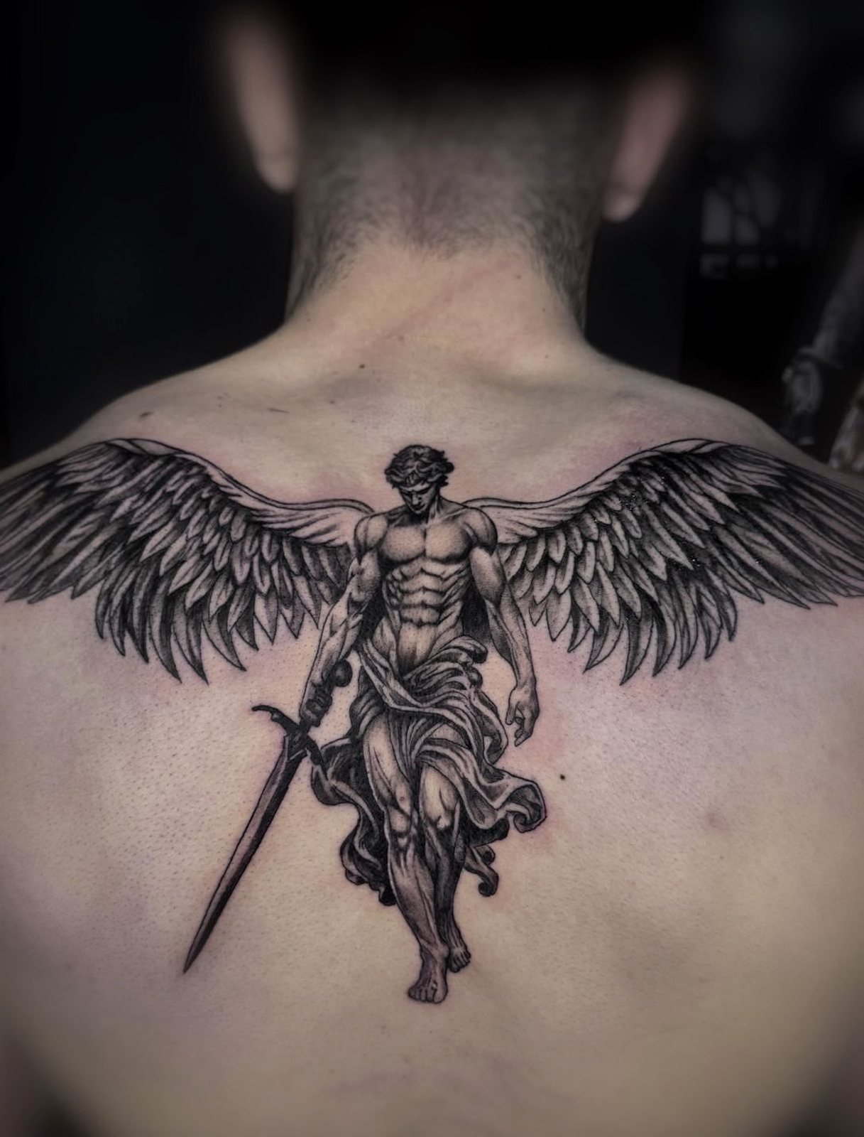 Ángel con espada sobre espalda